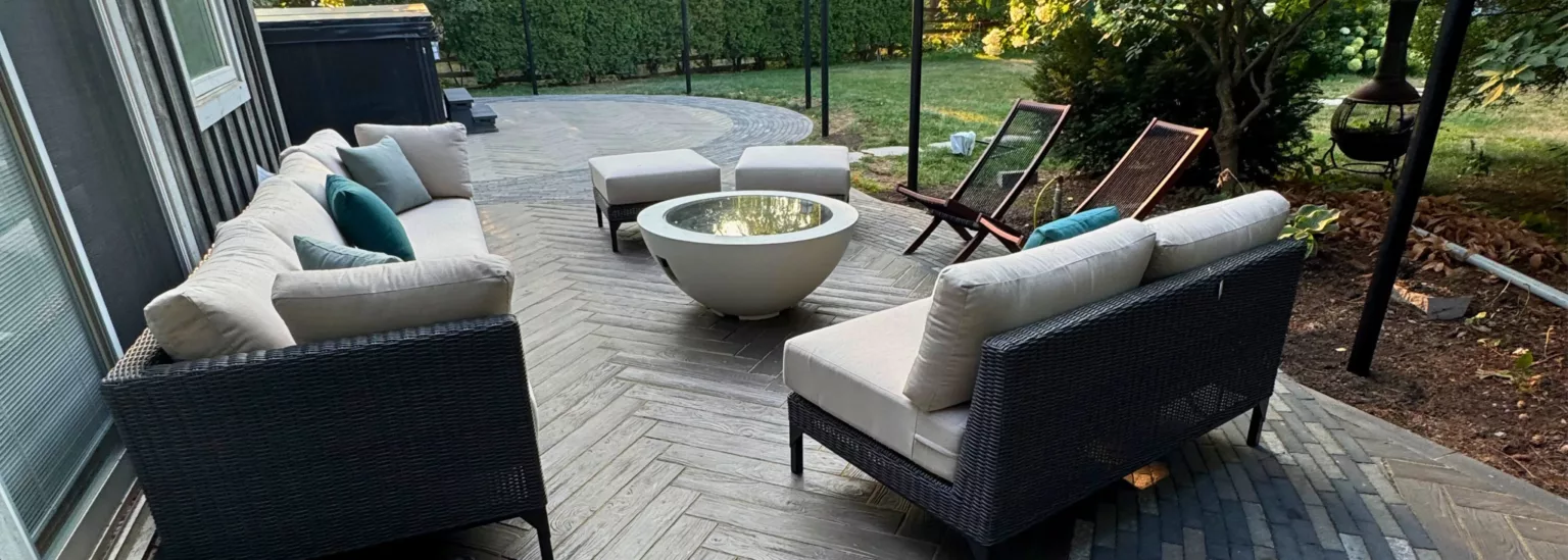 Backyard lounge with wicker sofas, fire pit, and curved walkway blending natural stone and modern pavers in Nashville, Ontario