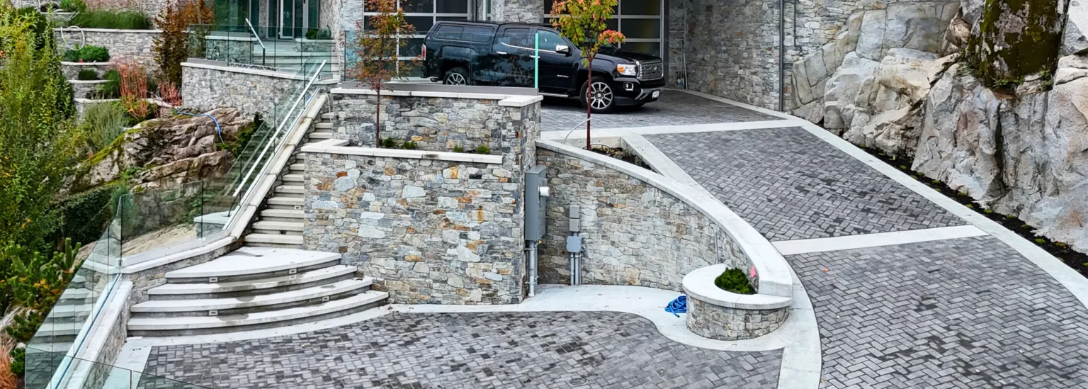 Curved heated driveway with herringbone paver design and stone retaining walls in West Vancouver, BC