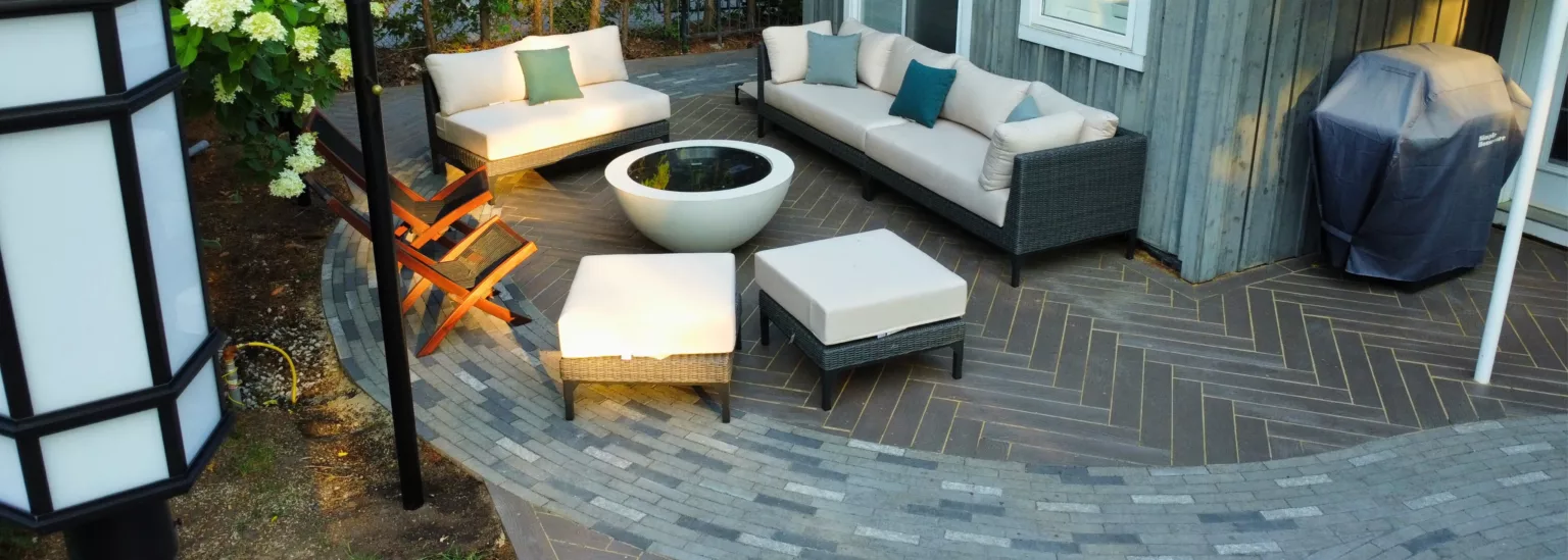 Outdoor lounge with modern furniture and curved patio borders using Unilock Mattoni pavers in Nashville, Ontario landscape project