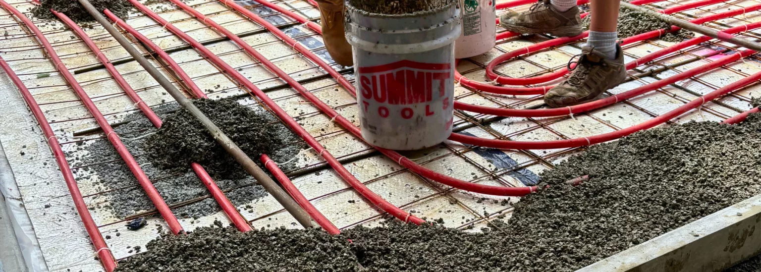 Radiant heating system installation with red tubing beneath driveway base layer in West Vancouver, BC