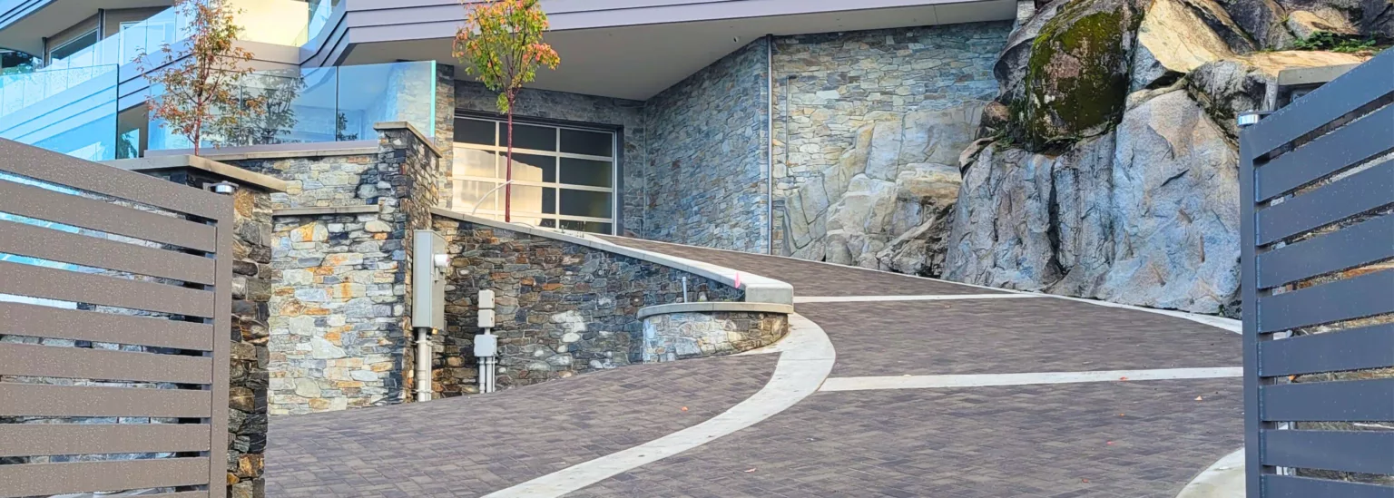 Steep modern driveway with stone walls and herringbone paver pattern in West Vancouver, BC residence